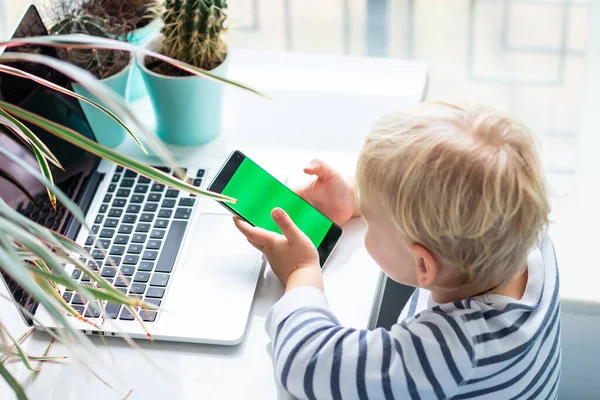 かわいい赤ちゃんの男の子を見て 携帯電話で遊んで 携帯電話のクロマキー緑の画面に焦点を当てる — ストック写真