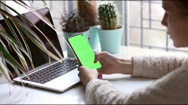 Küçük okul çocuğu izliyor, telefonda oynuyor, cep telefonunun yeşil ekranına odaklanıyor..