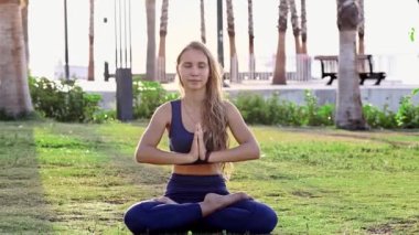 Güzel genç kız yoga yapıyor, yoga pozisyonunda dinleniyor yaz tatilinde gün doğumunda deniz kenarında poz veriyor.