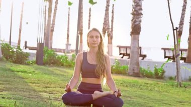 Güzel genç kız yoga yapıyor, yoga pozisyonunda dinleniyor yaz tatilinde gün doğumunda deniz kenarında poz veriyor.