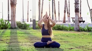 Güzel genç kız yoga yapıyor, yoga pozisyonunda dinleniyor yaz tatilinde gün doğumunda deniz kenarında poz veriyor.