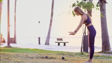 Güzel genç kız yoga yapıyor, yoga pozisyonunda dinleniyor yaz tatilinde gün doğumunda deniz kenarında poz veriyor.