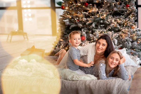 圣诞树旁快乐的家庭 早上妈妈和孩子们穿着睡衣在树旁玩乐 圣诞快乐及假期快乐的概念 — 图库照片