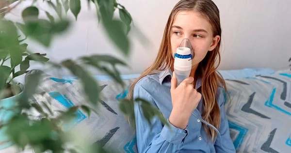10代の女の子はネブライザー装置で吸入を行います 手に吸入器を保持し 自宅で吸入器を介して呼吸する病気の子供 インフルエンザや気管支喘息のための理学療法 — ストック写真