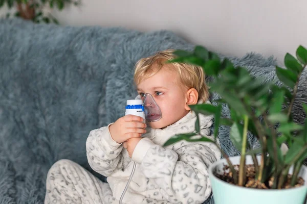 かわいい赤ちゃんの男の子は ネブライザー装置で吸入することができます 手に吸入器を保持し 自宅で吸入器を介して呼吸する病気の子供 インフルエンザや気管支喘息のための理学療法 — ストック写真