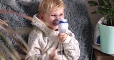 Sevimli erkek bebek nebulizör cihazıyla solunum yapıyor. Hasta çocuk elinde solunum cihazıyla evde solunum cihazından nefes alıyor. Soğuk algınlığı, grip ve bronşiyal astım tedavisi
