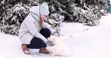 Mutlu genç kız kışın karda köpeğiyle oynarken eğleniyor. Kar oyunları. Kış tatili.