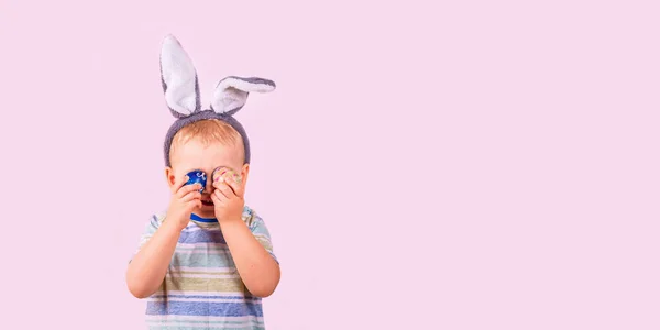 Милий Хлопчик Кролячих Вухах Голові Закриває Очі Кольоровими Яйцями Рожевому — стокове фото