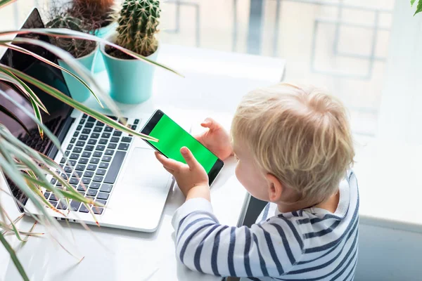 かわいい赤ちゃんの男の子を見て 携帯電話で遊んで 携帯電話のクロマキー緑の画面に焦点を当てる — ストック写真