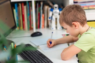 Evde dizüstü bilgisayarı ve sanal sınıfta ders çalışan küçük bir okul çocuğu. Karantina sırasında uzaktan eğitim ve öğrenme, e-öğrenme, çevrimiçi öğrenme kavramı