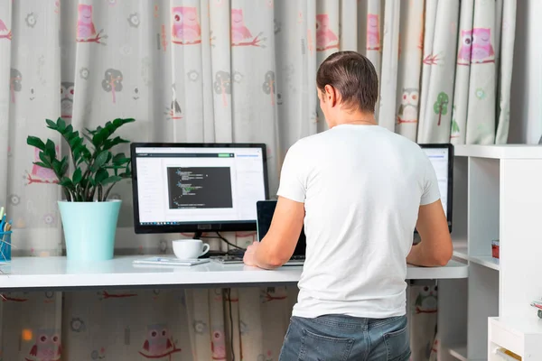Man working on computer at standing desk at home office. Freelancer working from home. High standing desk table comfortable for healthy back