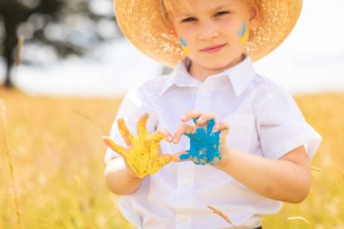 Ukrayna 'daki savaşı durdurun. Ukrayna kavramına bayılıyorum. Ukrayna bayraklı Ukraynalı çocuk ellerinde sarı ve mavi boya ile savaşa karşı duran bir kalp oluşturuyor..