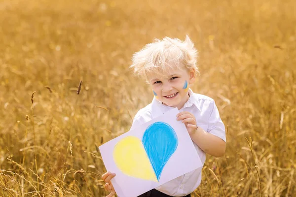 Stop War in Ukraine. Love Ukraine concept. Ukrainian boy with Ukrainina flag shaped as heart - yellow and blue stands against war.