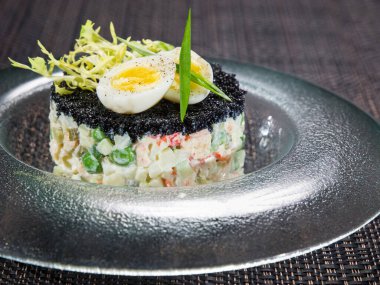 Geleneksel Rus sebze salatası, siyah havyar ve siyah hasır kaplama tabak.