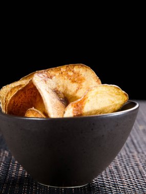 Koyu arkaplanda patates cipsi, dikey fotoğraf.