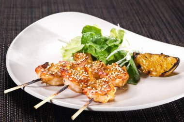 Bir porsiyon ızgara karides şiş salata karışımı ve koyu arkaplanda ızgara limon, yatay fotoğraf.