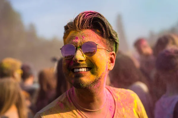 Yakışıklı, gülümseyen siyah saçlı adam Holi renk festivalinde eğleniyor.