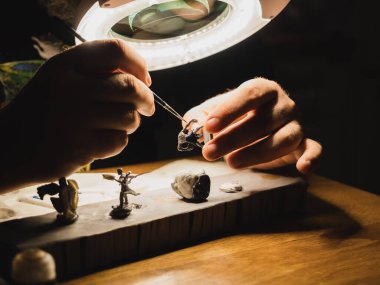 Lambanın altını ışık ve büyüteç ile boyamış insan elleri masa oyunları için plastik minyatürler, modern oyun koleksiyoncusu hobisi