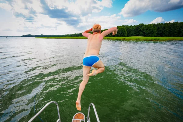 Young Man Jumping Sailing Yacht Deck Lake View Back — стоковое фото