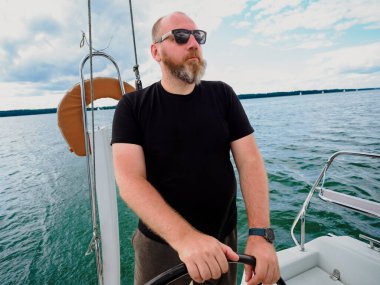 Yetişkin sakallı adam direksiyon Bir yelkenli yat