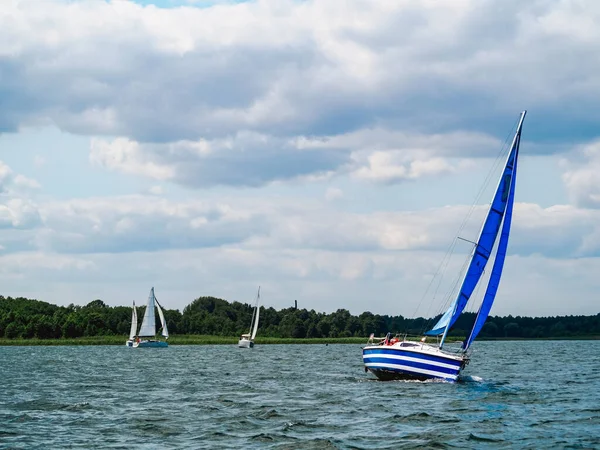 Mavi yelkenli yelkenli Rüzgarlı bir yaz gününde bir gölde yelken açıyor
