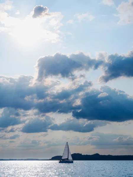 sailing yacht or sailboat on full sails swims on a lake in a windy sunny day