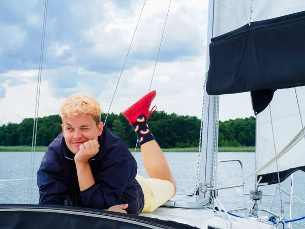 handsome person laying on yacht deck and enjoying on a sailing yacht on summer vacations