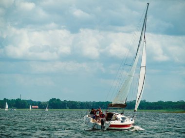 Güneşli bir yaz gününde, bir gölde yelken açan yelkenli.