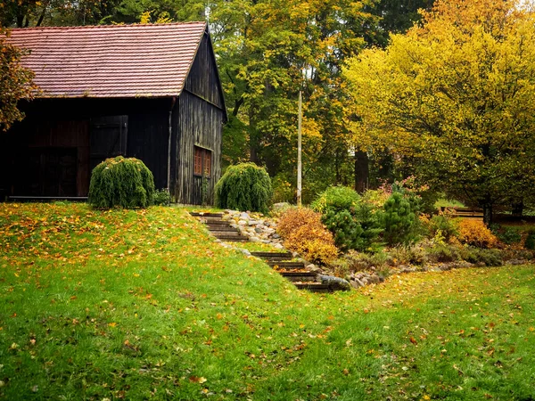 black wooden old hut on a backyard of a countryside farm in autumn golden foliage season