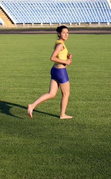 草の上を実行している美しい 10 代のスポーツの女の子. — ストック写真