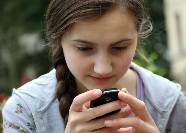 Flicka som leker på mobiltelefon — Stockfoto