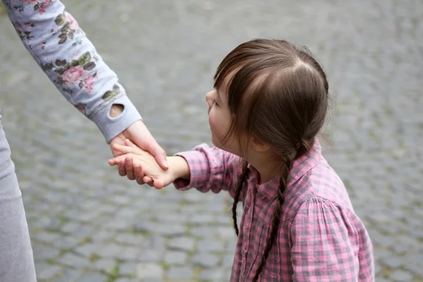 Chica sosteniendo el brazo de la madre en un paseo —  Fotos de Stock