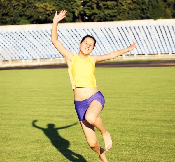 Bela adolescente esporte menina correndo na grama do estádio . — Fotografia de Stock