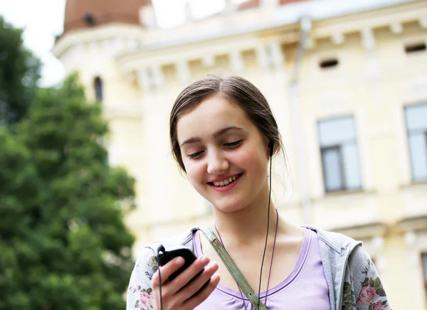 Dívka poslech hudby v mobilním telefonu v městě — Stock fotografie