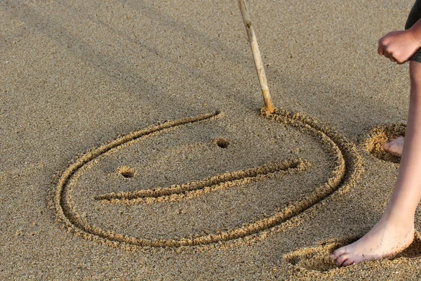 Una cara sonriente dibujando en una arena . — Foto de Stock