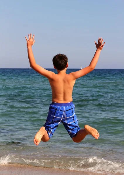 Chłopiec skacze na plaży nad morzem na wakacje — Zdjęcie stockowe