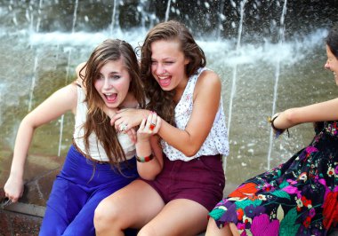 Beautiful girls having fun with a fountain. clipart