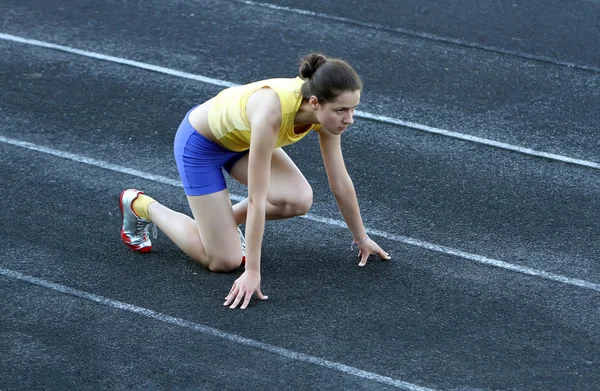 Sportovní dospívající dívka v počáteční pozici na trati . — Stock fotografie