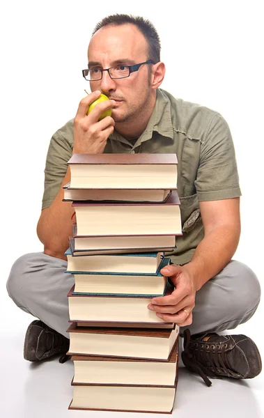 Jovem sentado ao lado de pilha de livros — Fotografia de Stock