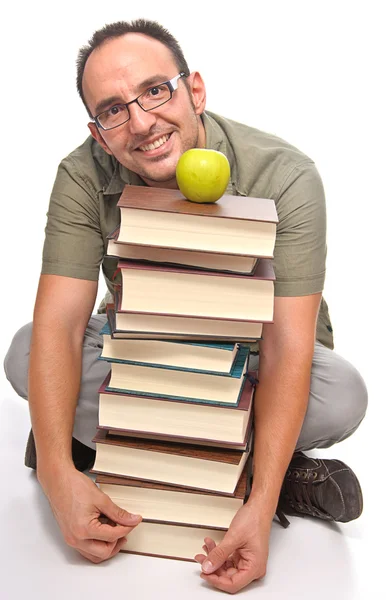 Jovem sentado ao lado de pilha de livros — Fotografia de Stock