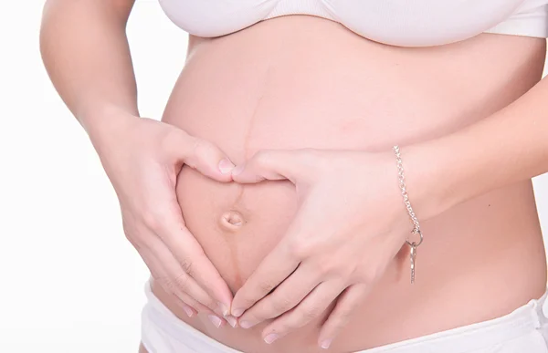 Pregnant woman with heart shaped hands on her belly — Stock Photo, Image