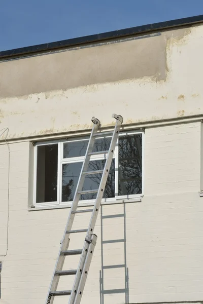 Ladder leaning against wall with window — Stock Photo, Image