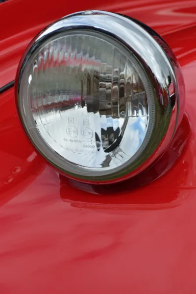 Detail of car headlamp on red in portrait — Stock Photo, Image