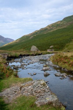 Cumbria Gölü bölgesindeki Honister Geçidi 'nde arka planda dağları olan akarsu