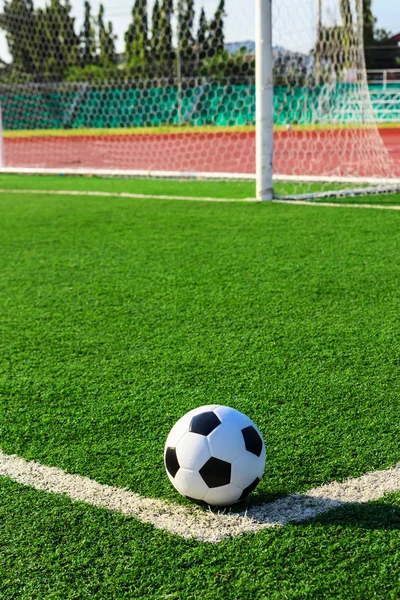 Bola de futebol na grama verde na frente da rede gol — Fotografia de Stock