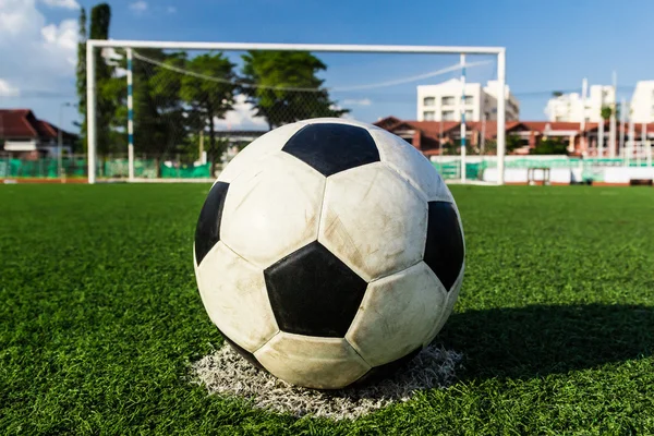 Soccer ball on green grass in front of goal net — Stock Photo, Image