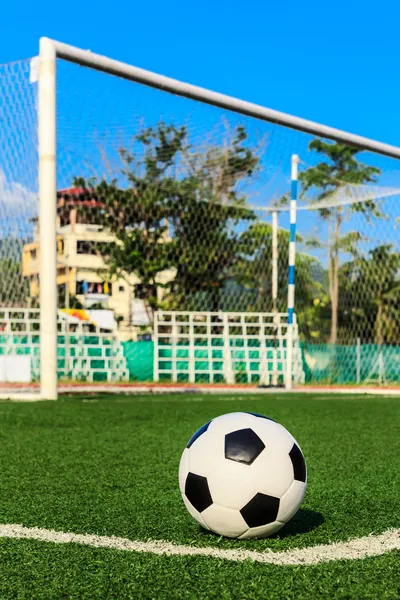 Soccer ball on green grass in front of goal net — Stock Photo, Image