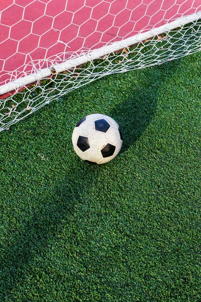 Fotboll på grönt gräs i netto målet — Stockfoto