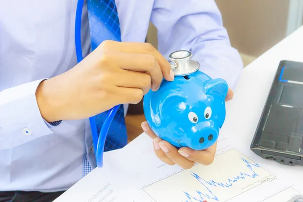 Biznesmen z stetoskop sprawdzanie piggy bank, finansowy di — Zdjęcie stockowe