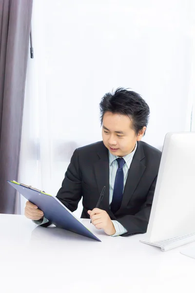 Hombre de negocios que trabaja con bloc de notas y computadora de escritorio —  Fotos de Stock